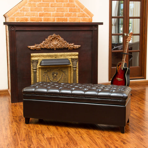 Dark brown tufted storage ottoman with ornate fireplace and acoustic guitar
