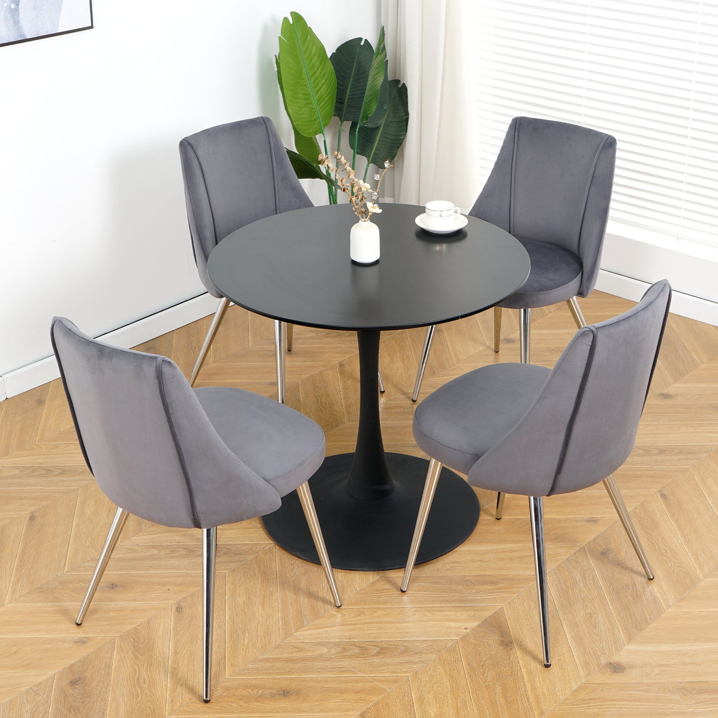 Gray velvet dining chairs with chrome legs around black tulip dining table