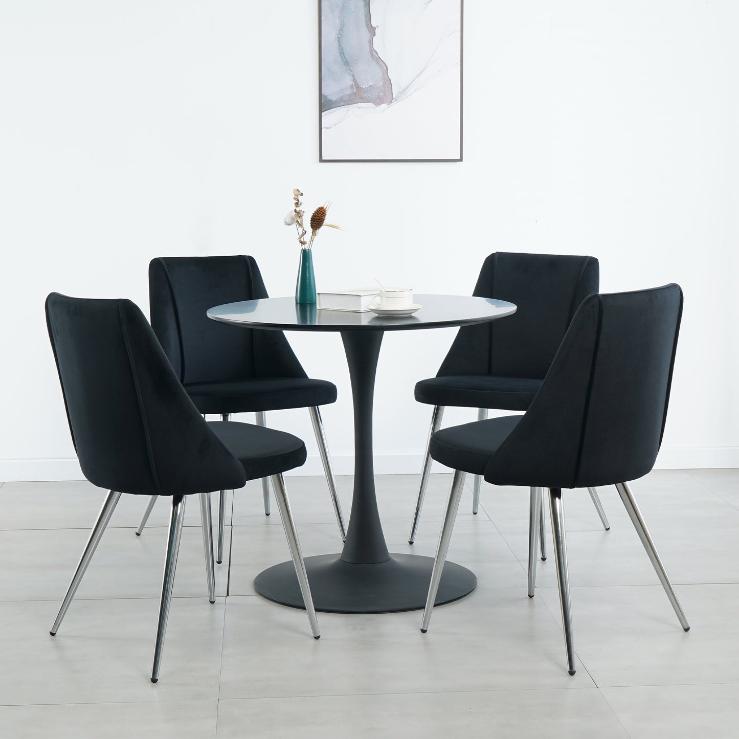 Four black velvet dining chairs with chrome legs around a round pedestal table