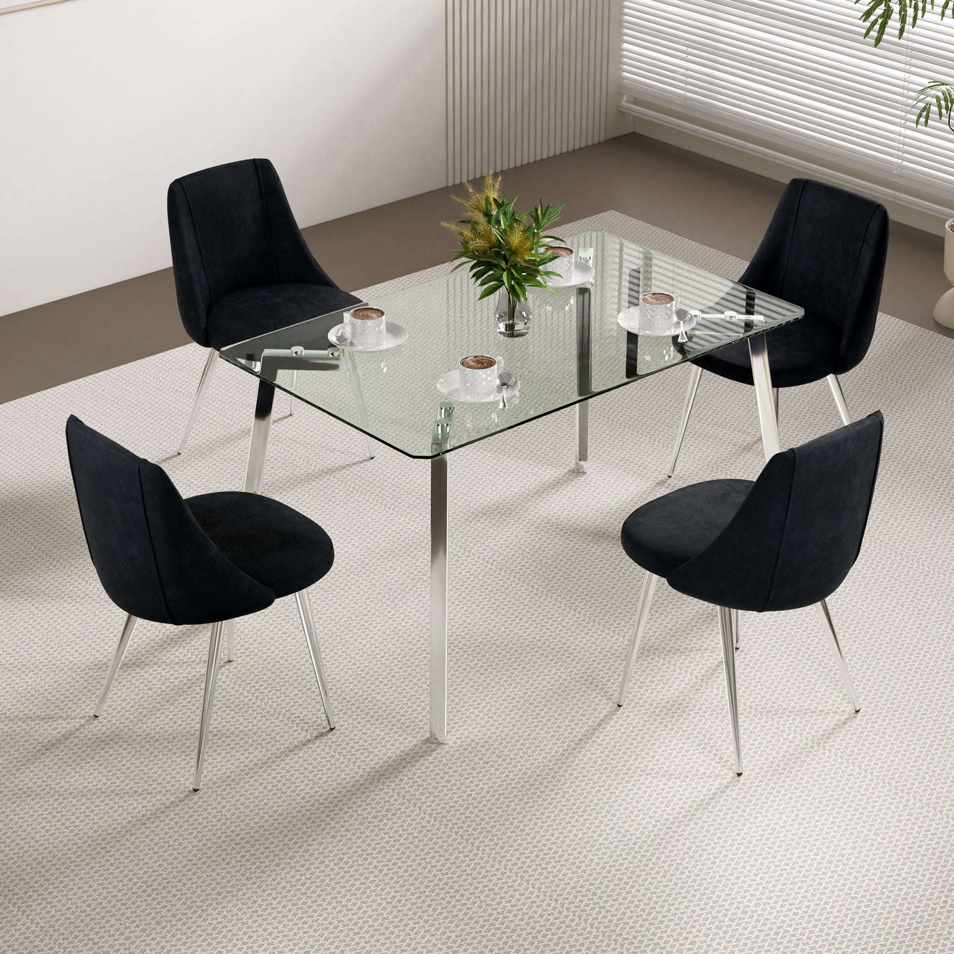 Modern black velvet dining chairs with sleek chrome legs around a glasstop dining table