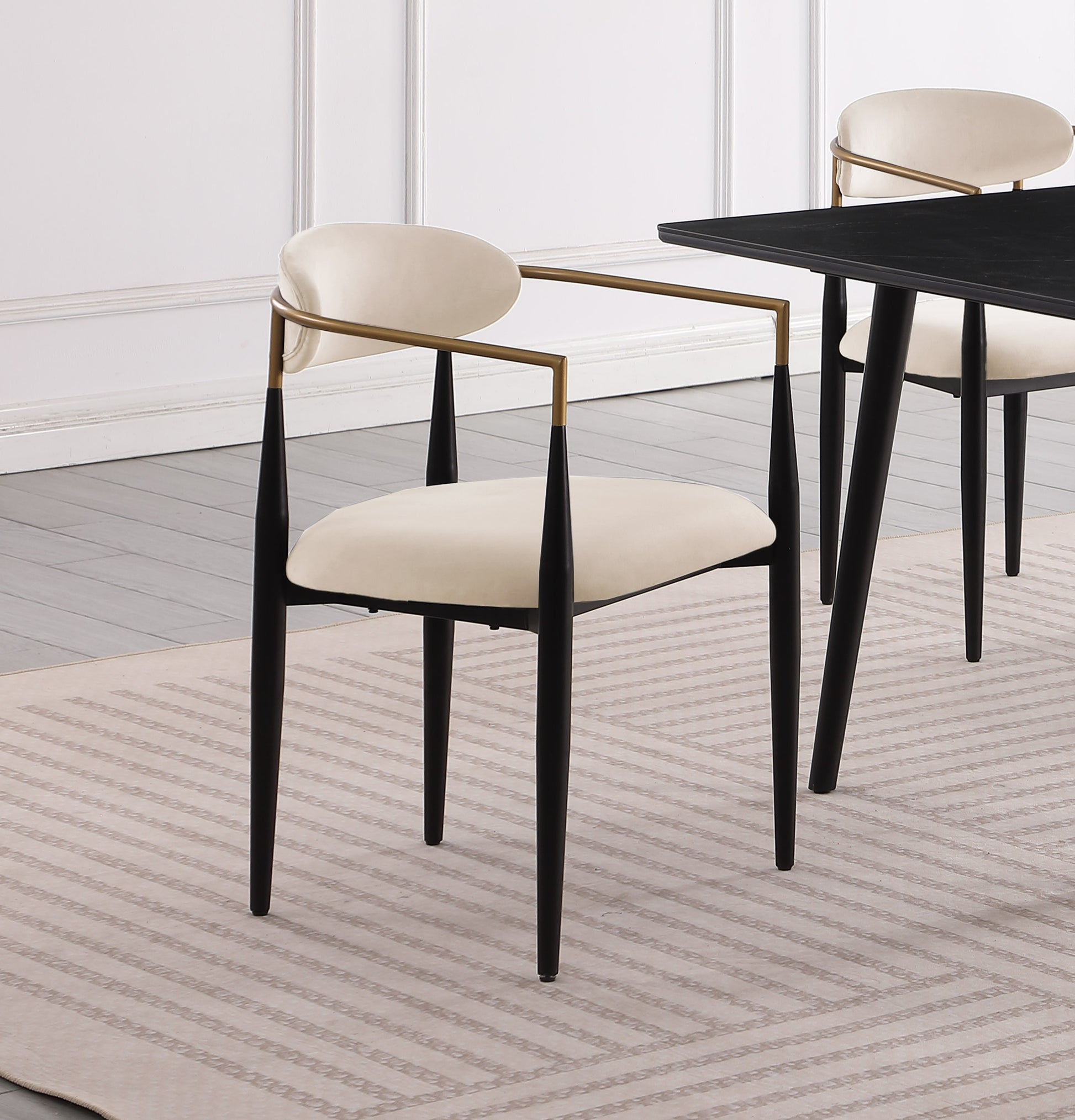 Cream upholstered dining chair with gold arms and black tapered legs