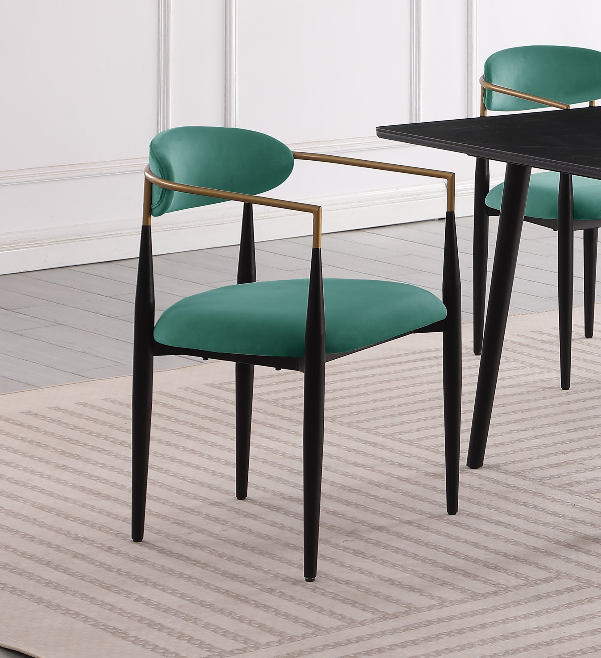 Emerald green velvet dining chair with gold arms and black legs
