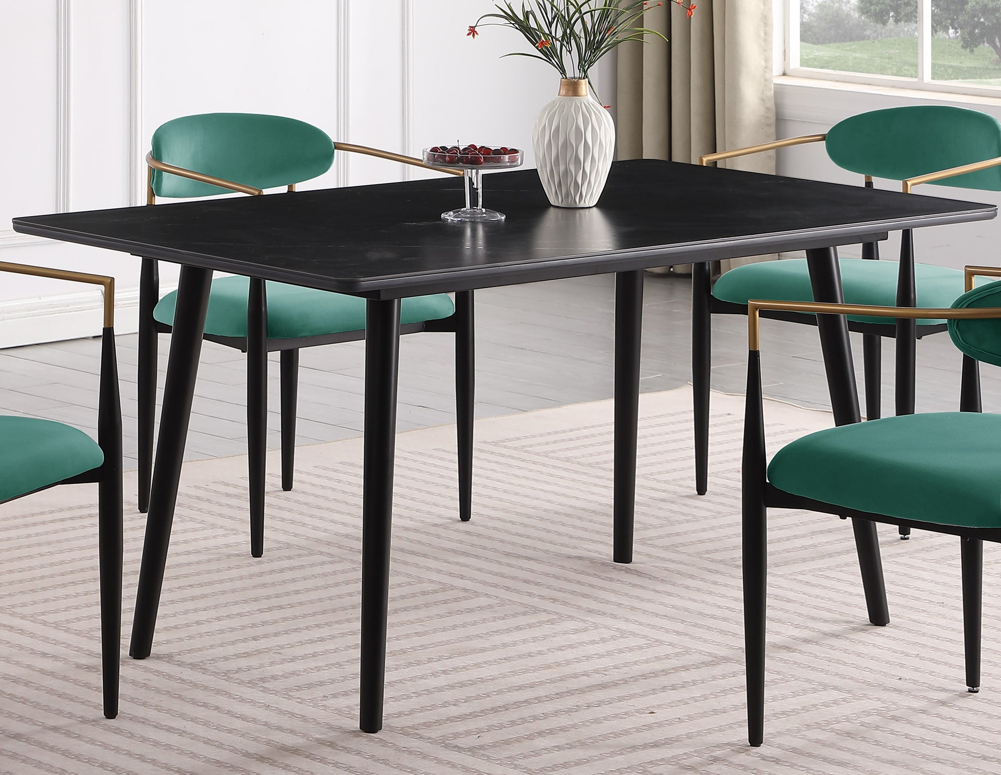 Black modern dining table with tapered legs paired with emerald green velvet chairs