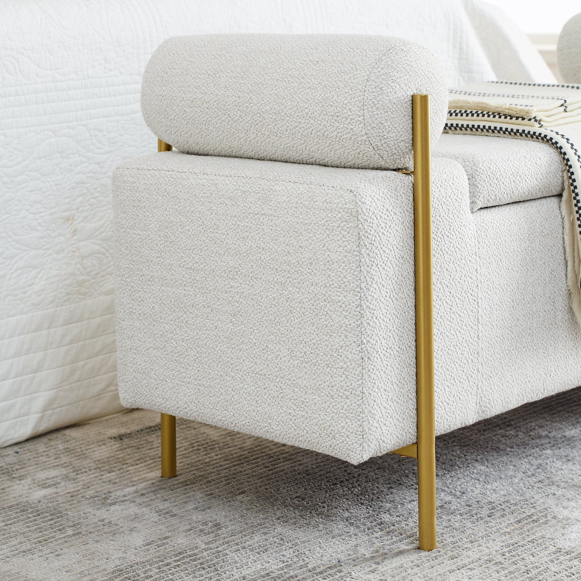 Textured cream bench with brass legs beside a white bed