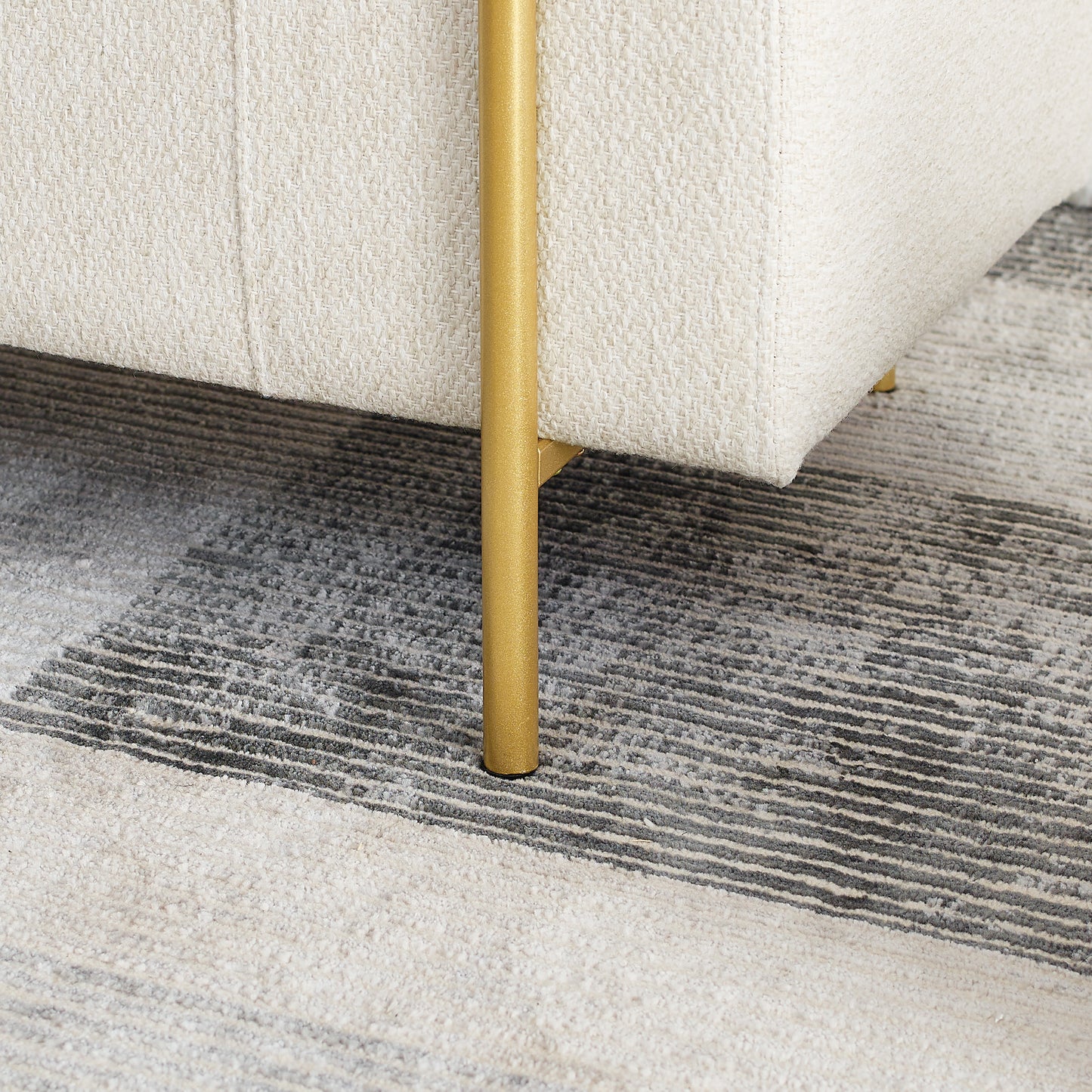 Cream textured sofa detail with gold leg on abstract rug
