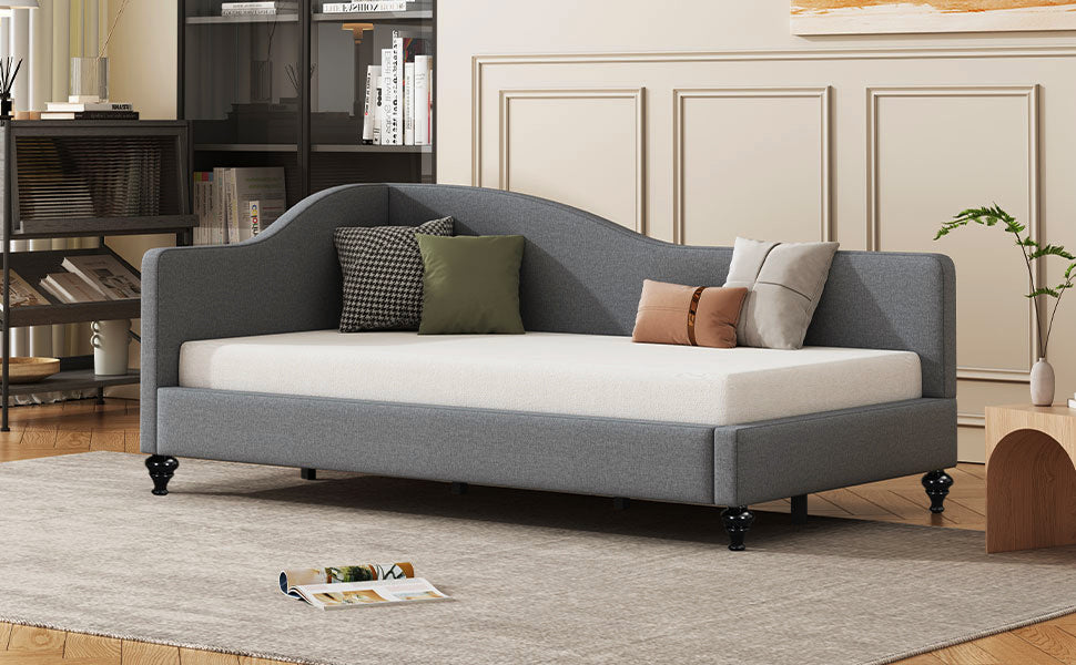 Gray upholstered daybed with curved back and decorative pillows