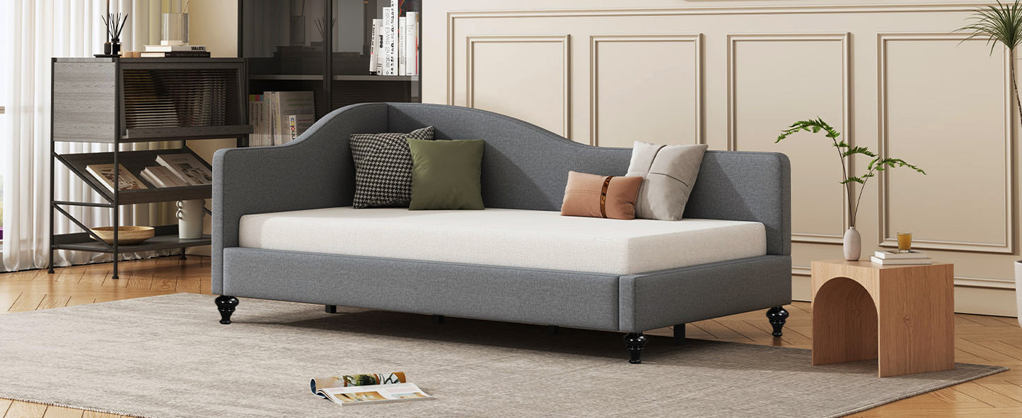 Gray upholstered daybed with arched back and decorative pillows