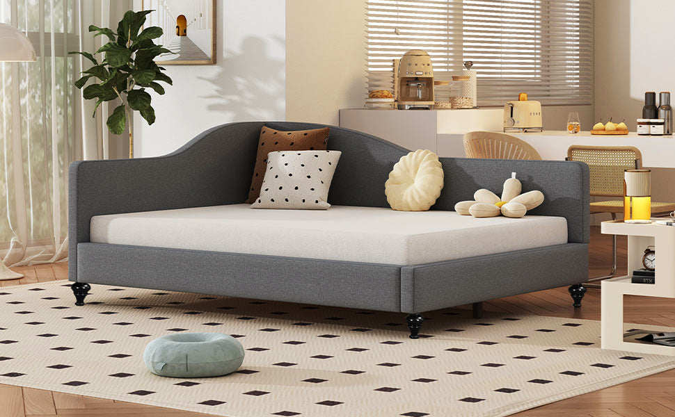 Gray upholstered daybed with curved back and tufted pillows for a stylish living room