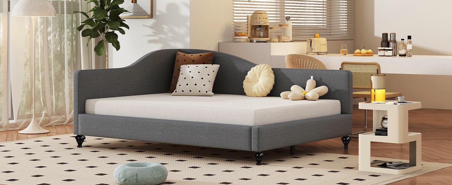 Dark gray upholstered daybed with curved back and tufted pillows