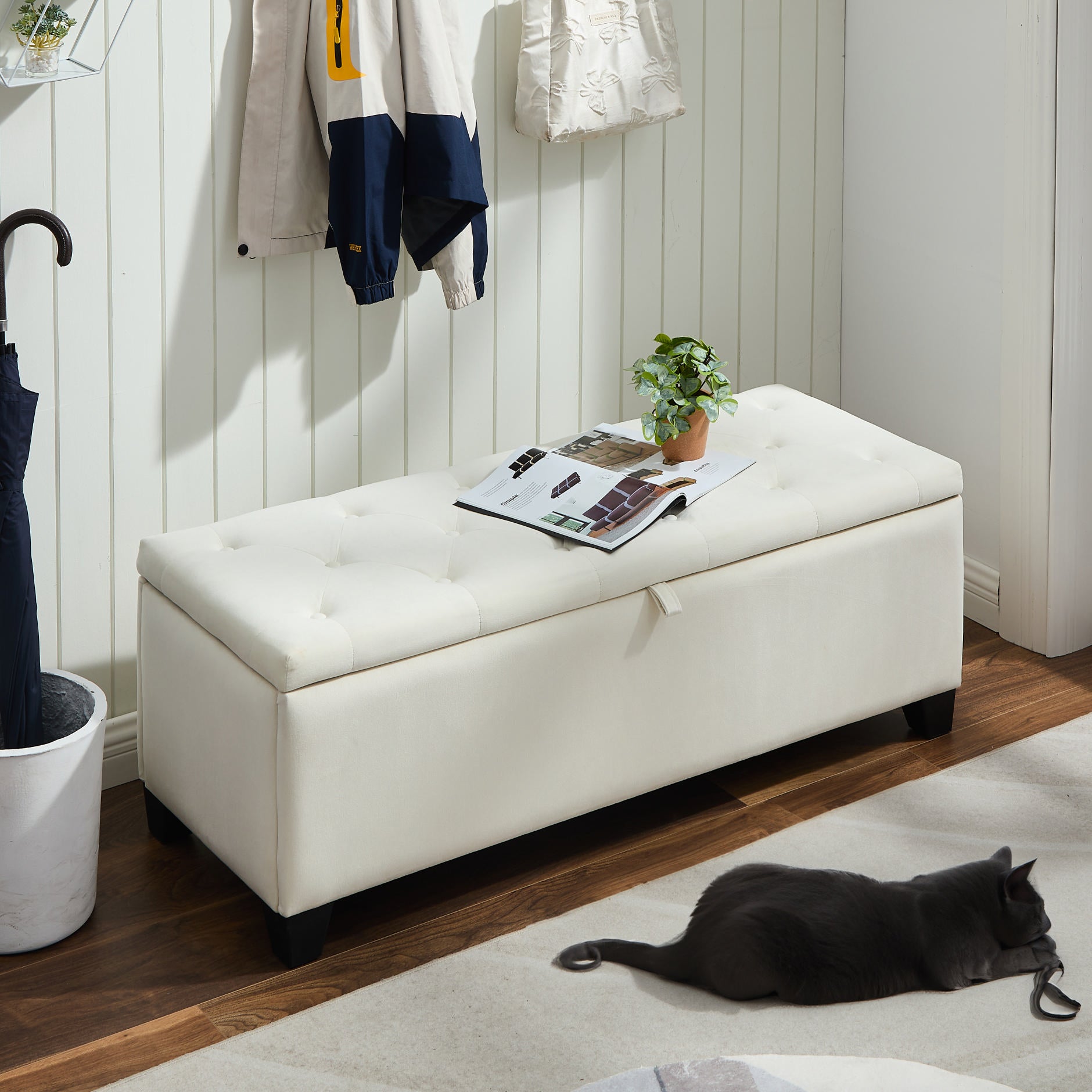 Tufted cream storage bench with magazine and plant