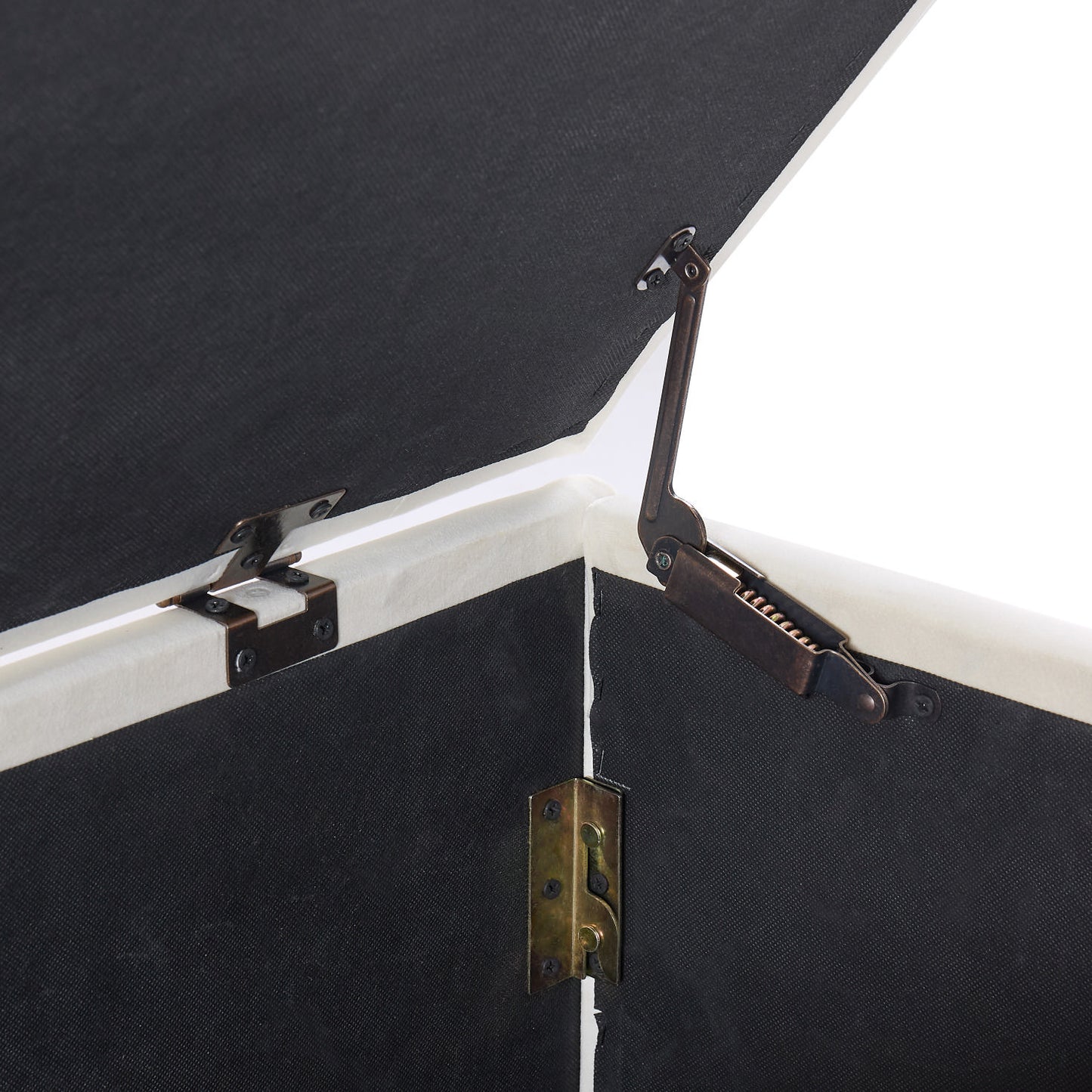 Closeup of dark fabric lining with antique brass lid support hinges on an ottoman