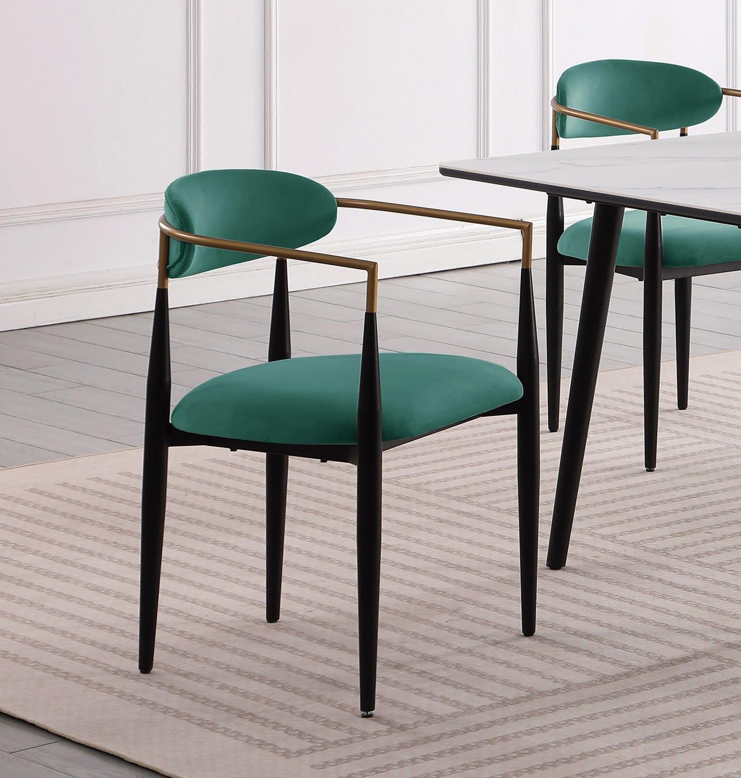 Emerald green velvet dining chair with gold arms and black tapered legs