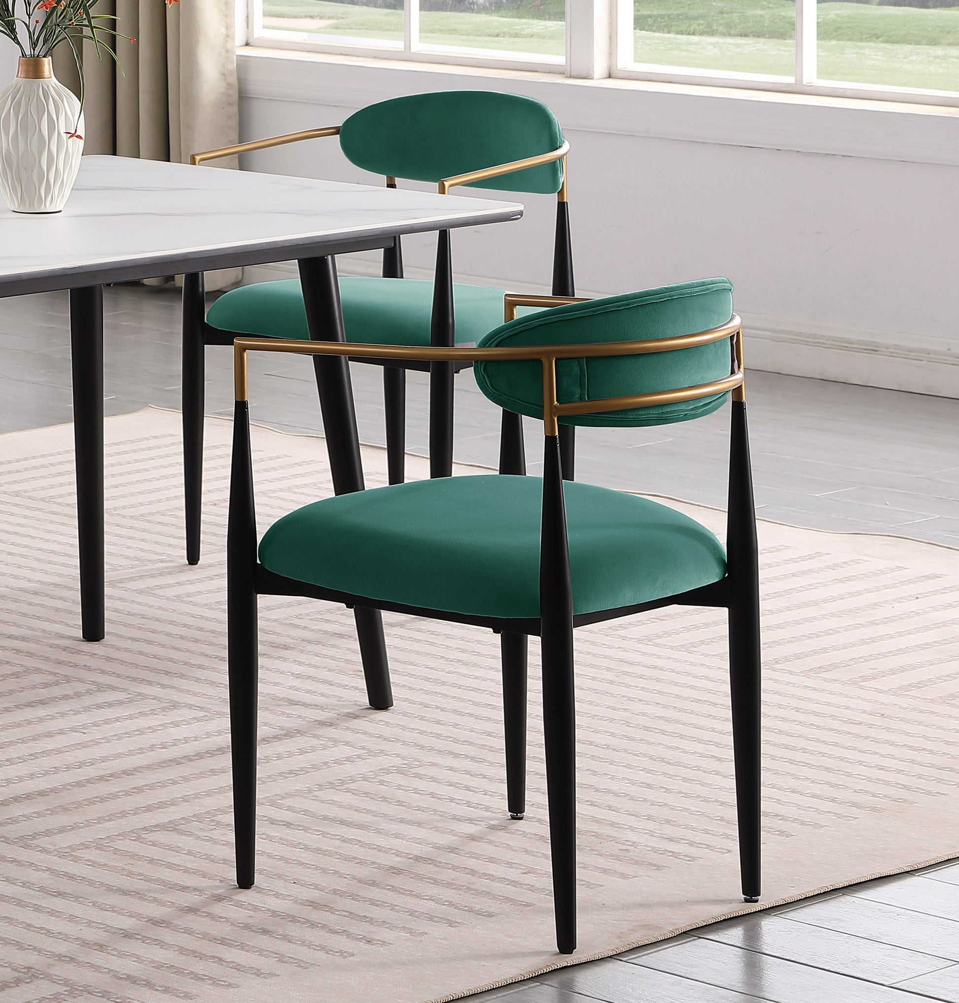 Emerald green velvet dining chair with gold accents and black legs