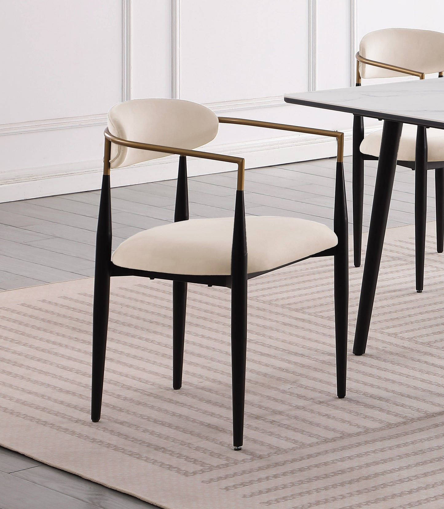 Cream upholstered dining chair with black tapered legs and gold arms