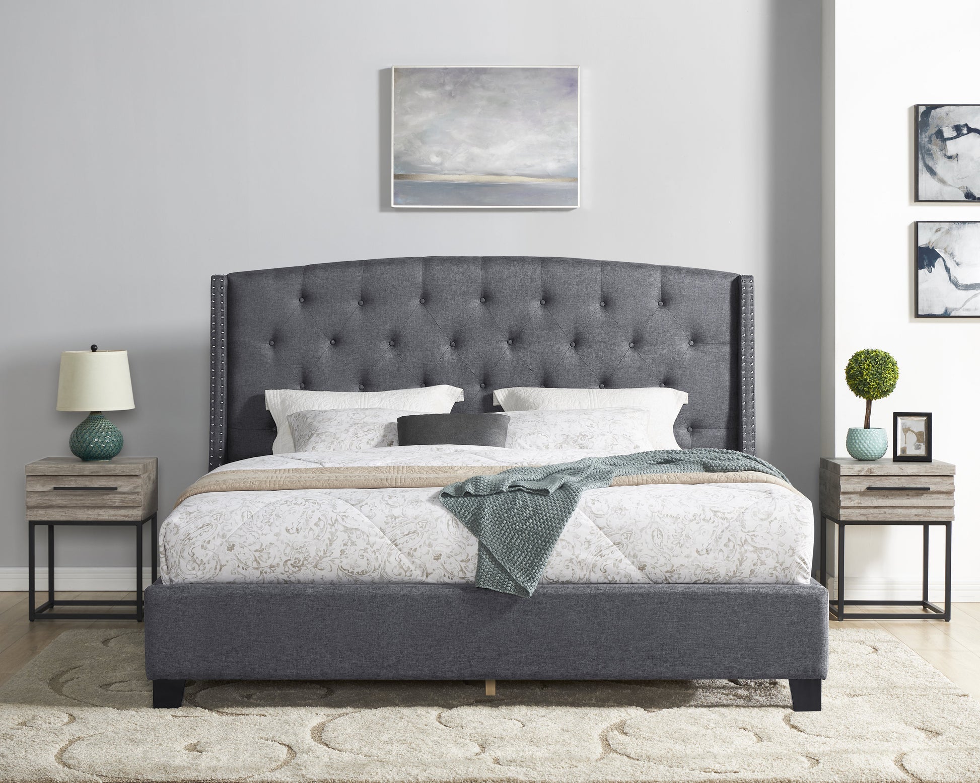 Dark gray upholstered platform bed with diamond tufting and silver nailhead trim