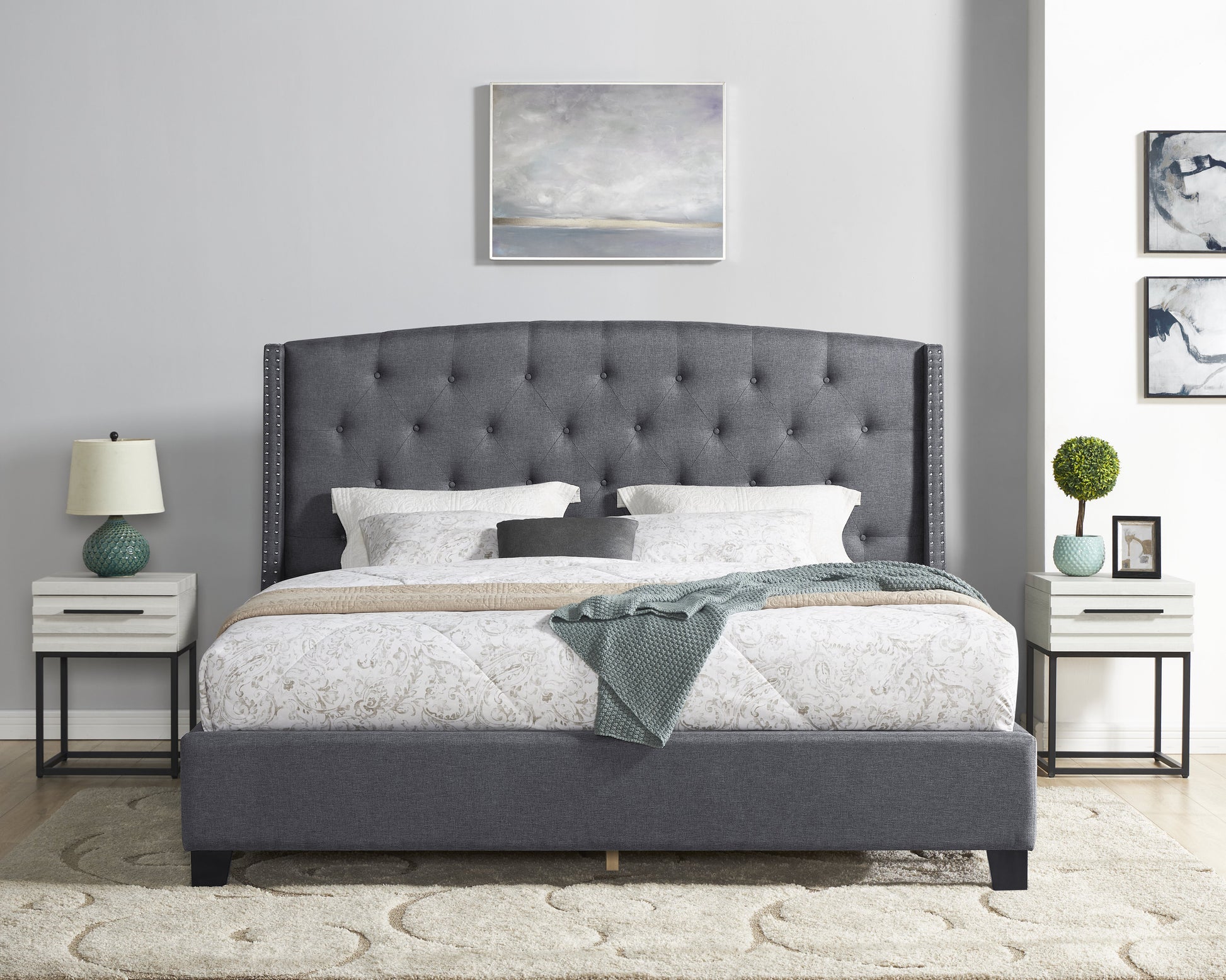 Dark grey fabric upholstered bed with tufted headboard and nailhead trim