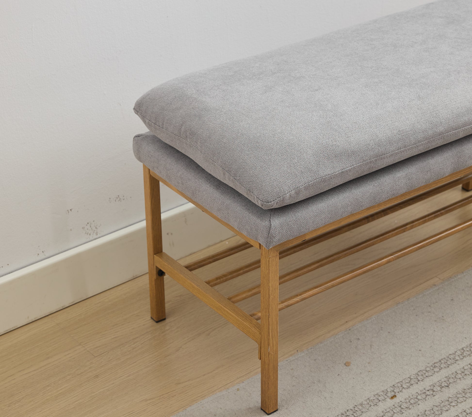 Grey upholstered storage bench with duallayer cushion and slatted wooden shelf