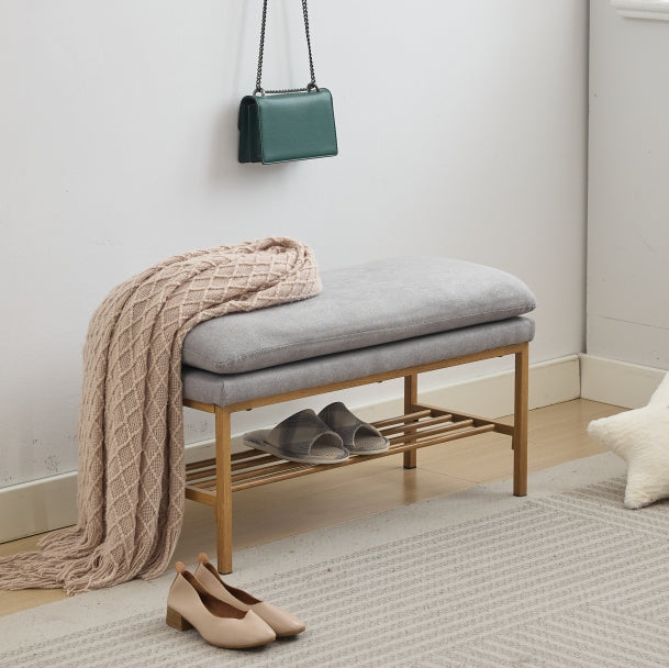 Gray upholstered bench with shoe rack and draped throw