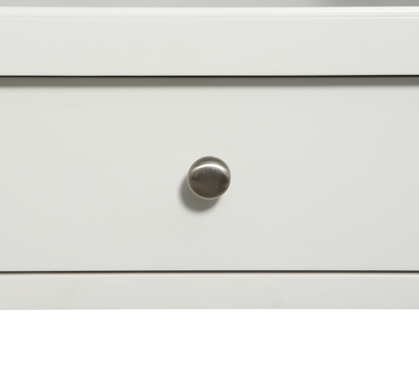 Closeup of a white dresser drawer front with a brushed nickel knob