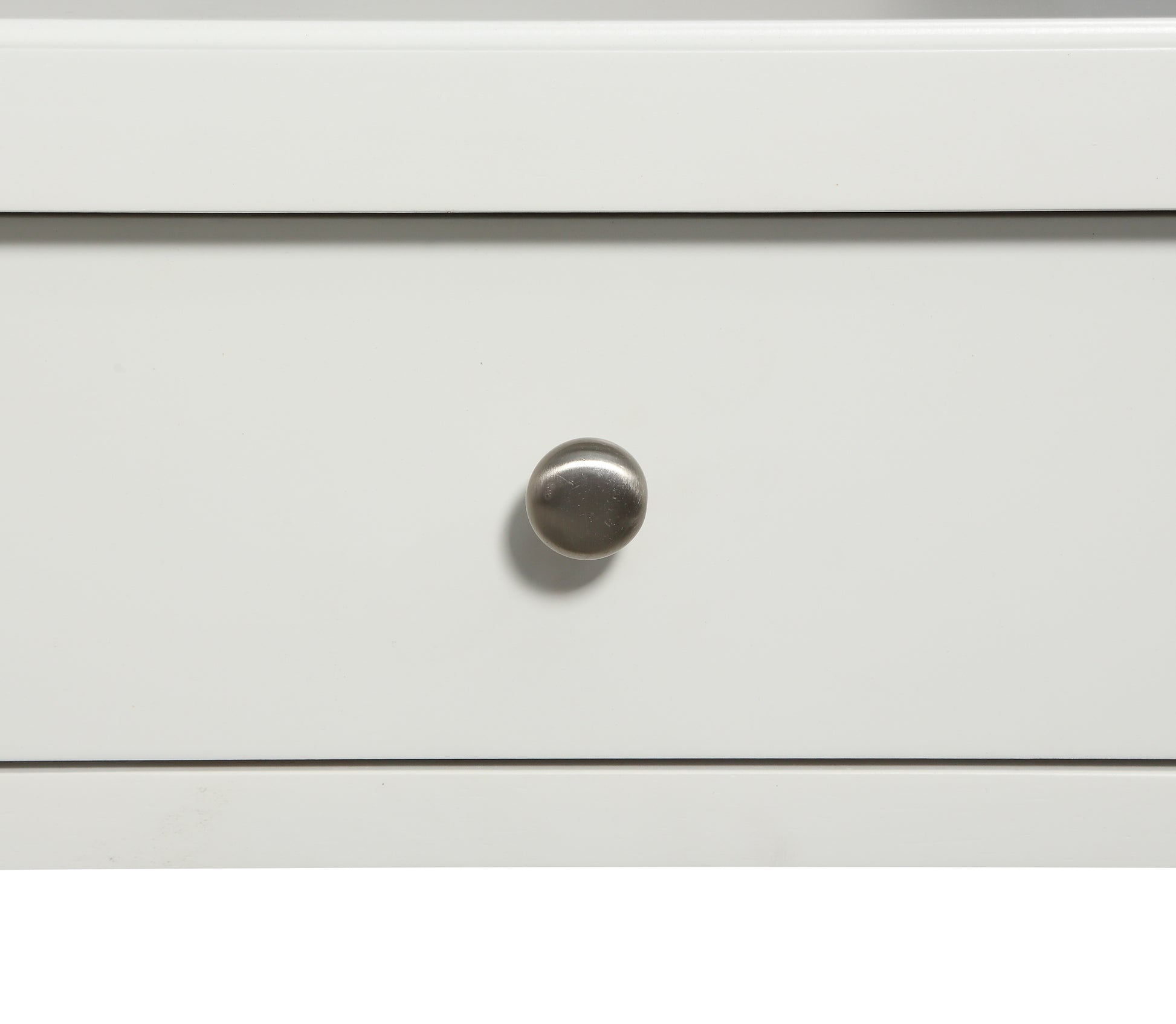 Closeup of a white dresser drawer front with a brushed nickel knob
