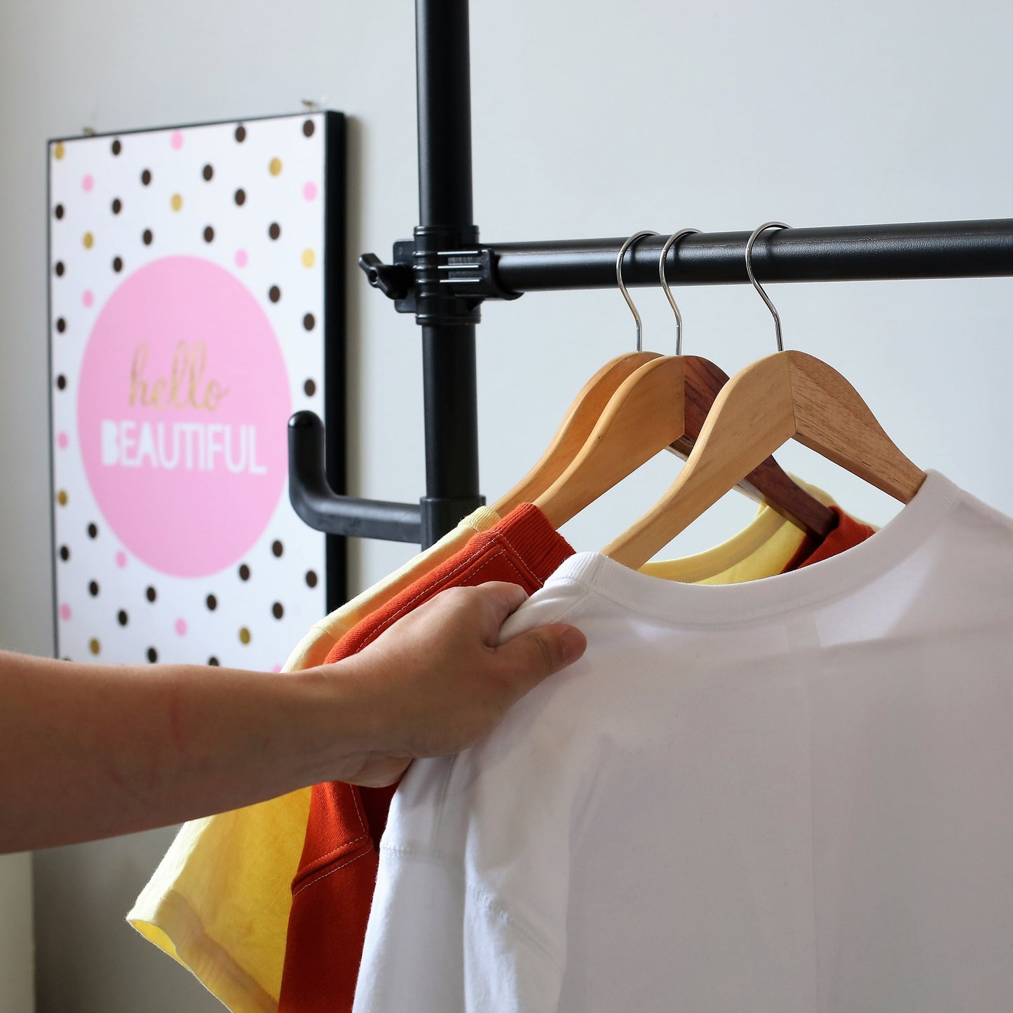 Hand selecting a white crewneck tshirt from a rack with colorful shirts