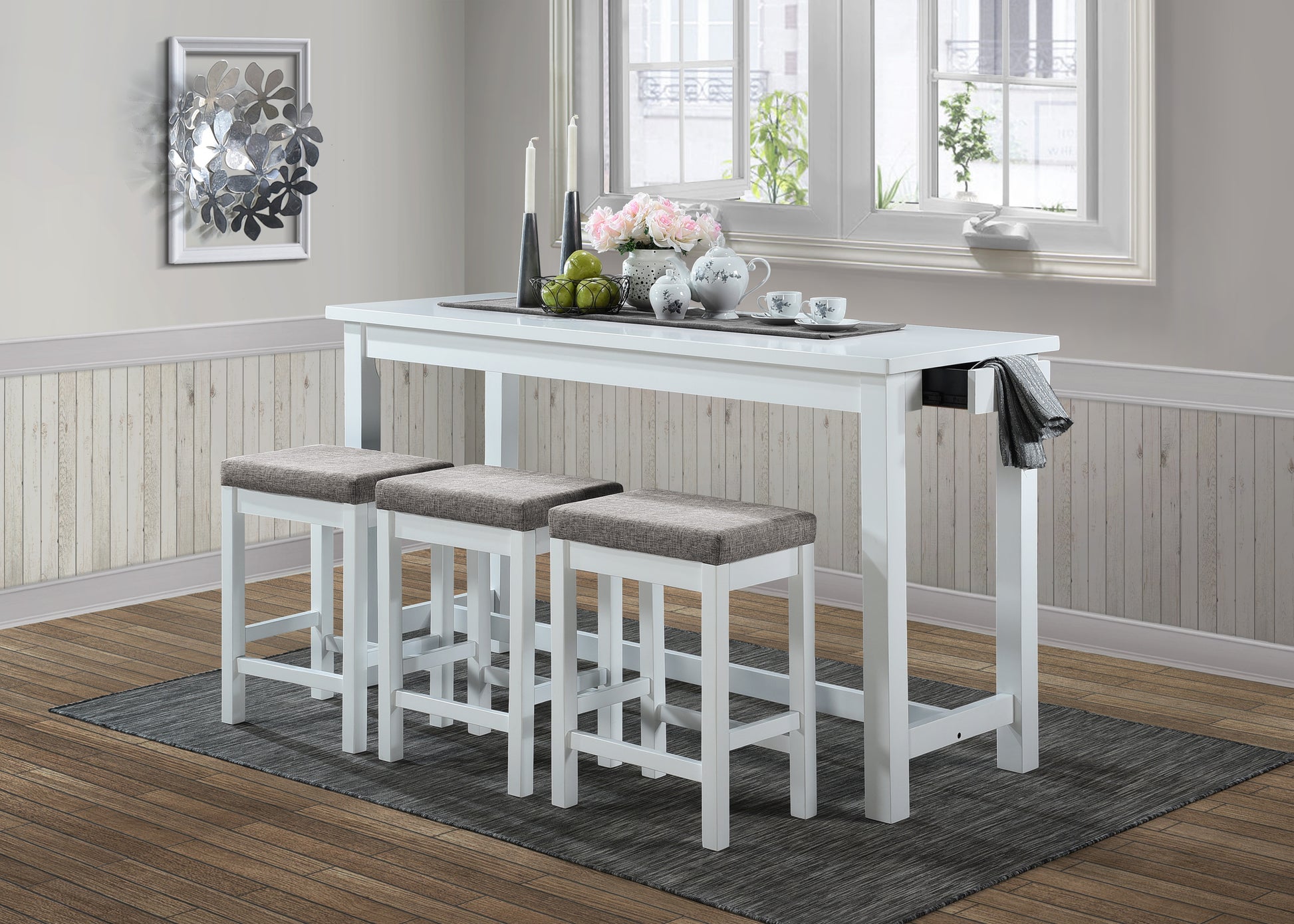 White counter height dining table with three grey upholstered stools in a modern setting