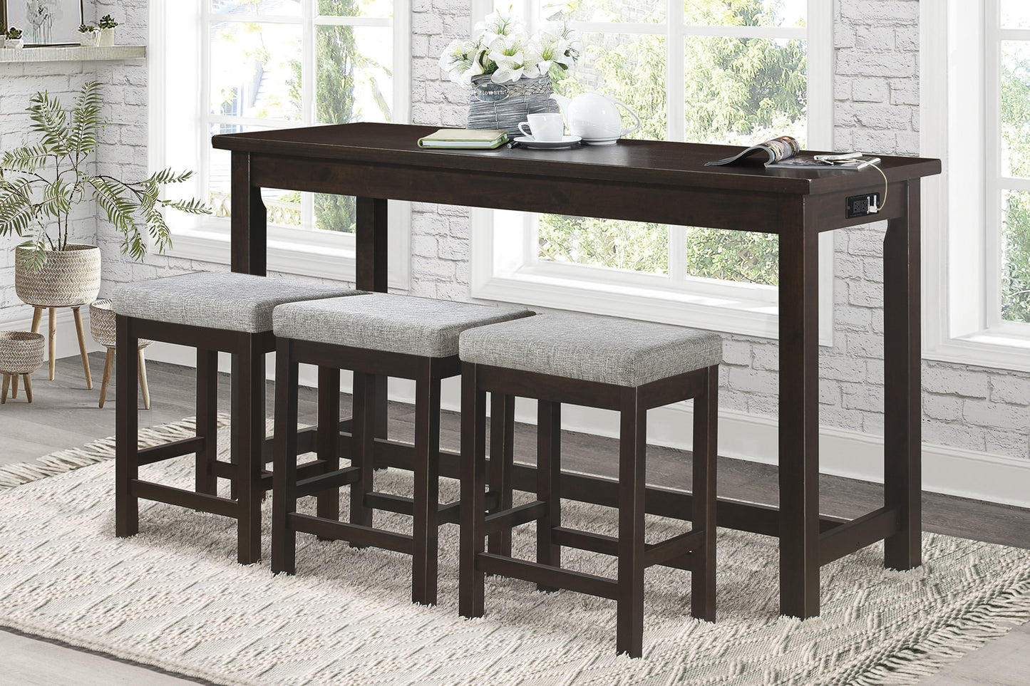 Dark wood counter height table with three gray upholstered stools and builtin power outlets