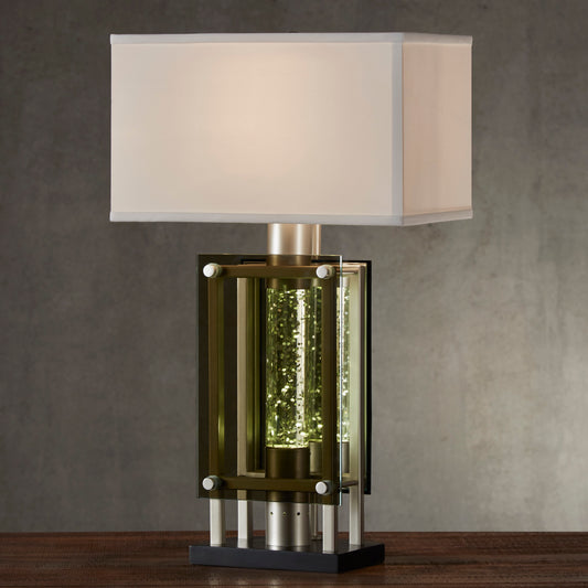 Modern desk lamp with a clear glass cylinder filled with shimmering golden accents