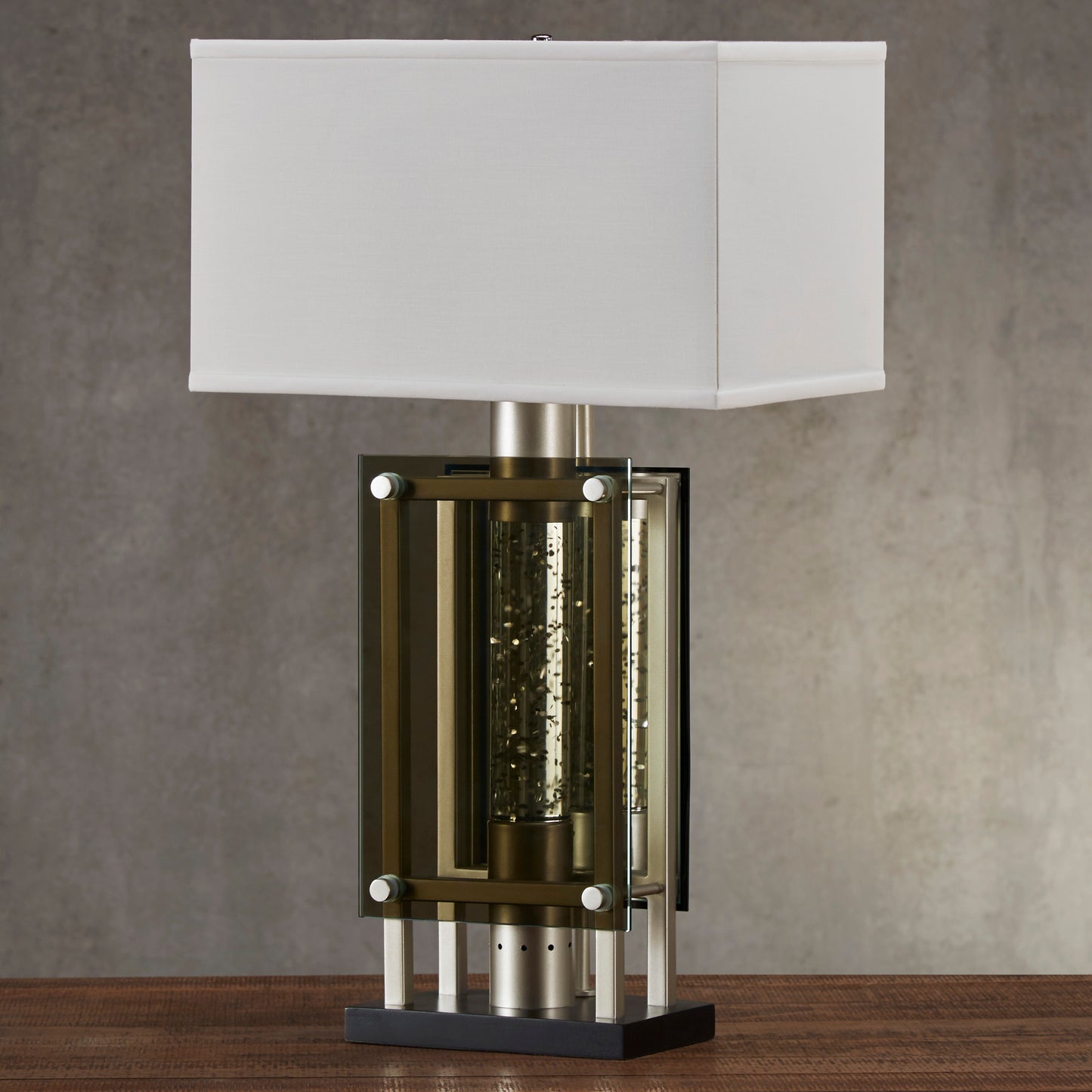 Brushed nickel table lamp with clear glass cylinder showcasing gold flecks and white square shade