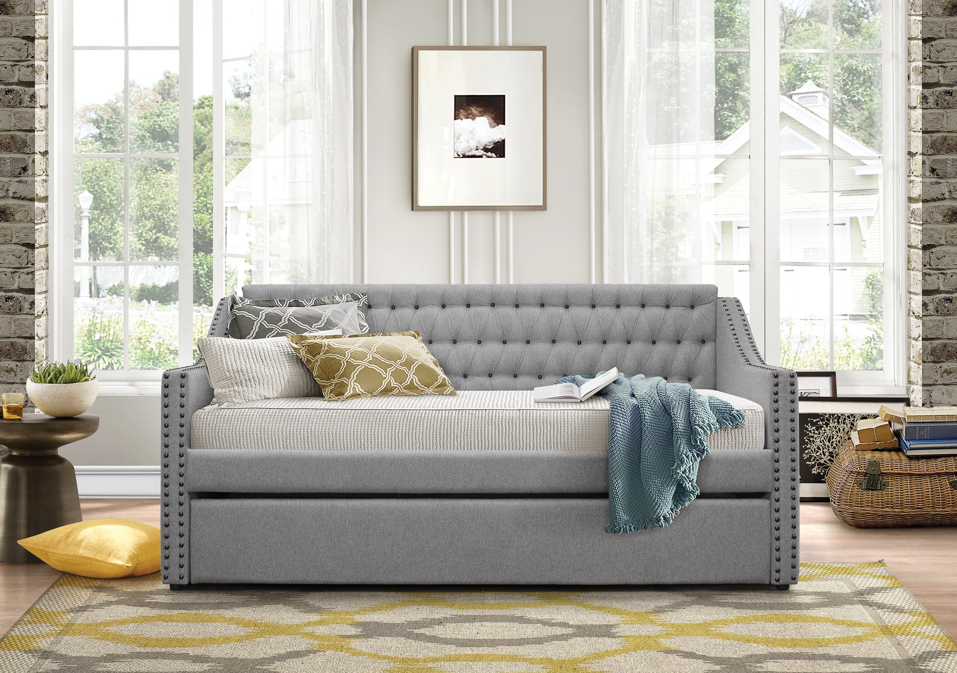 Tufted grey fabric daybed with decorative nailhead trim and throw pillows