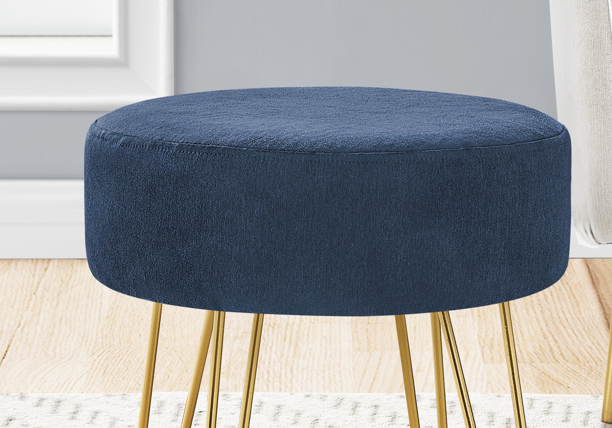 Round navy blue fabric ottoman with gold hairpin legs