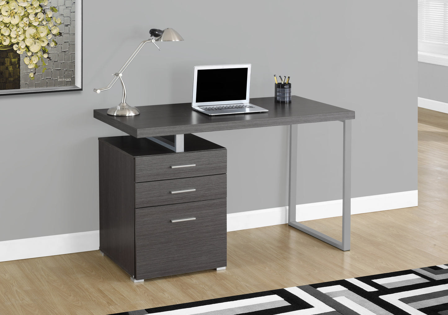 Modern dark grey wood computer desk with three drawers and silver legs