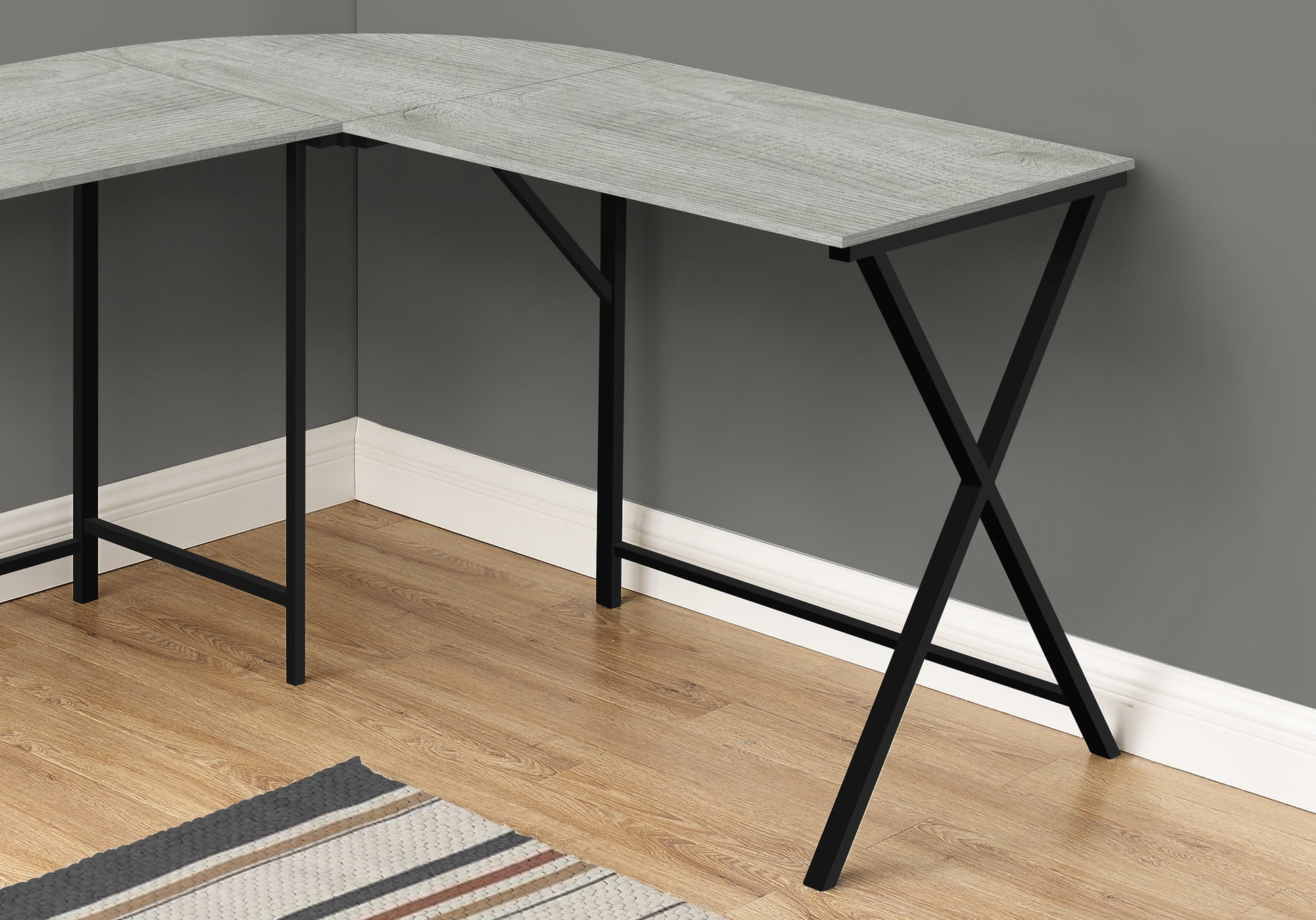Lshaped gray wood grain laminate desk with black metal legs and Xcross bracing