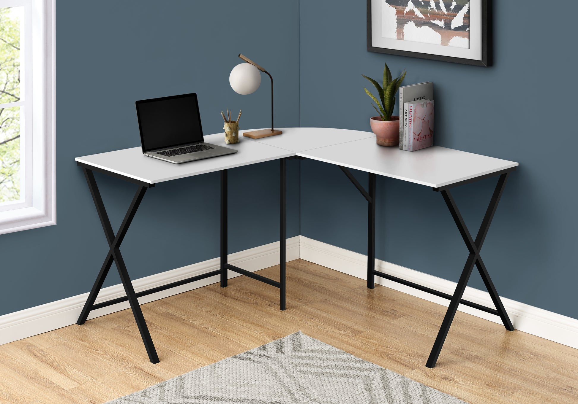 White Lshaped desk with black Xframe legs and laptop