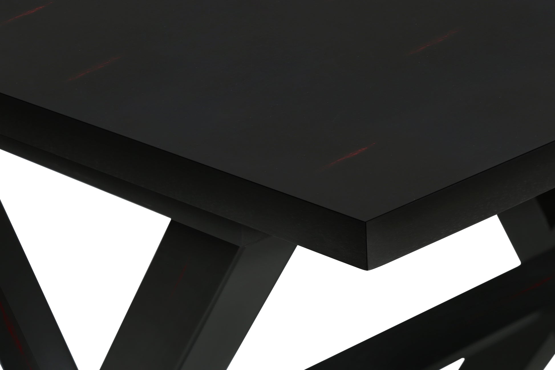 Closeup of a black dining table with subtle red wood grain details on its surface