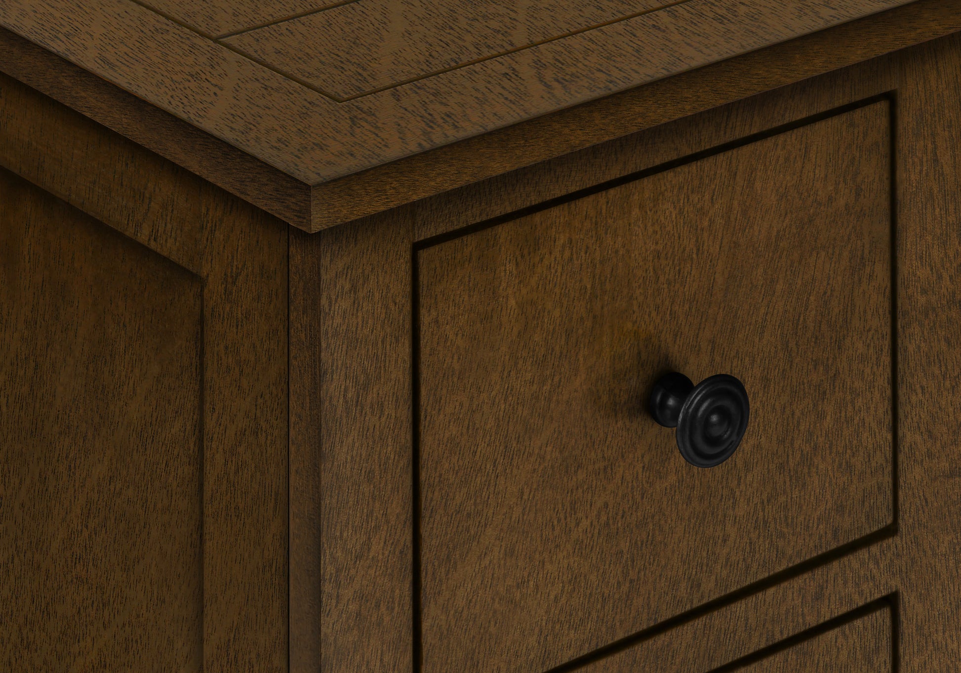 Closeup of dark brown wooden cabinet with inset drawers and black round knob
