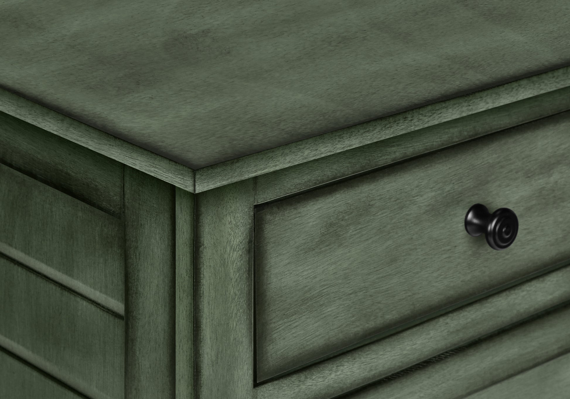 Closeup of weathered sage green wood nightstand drawer with black knob