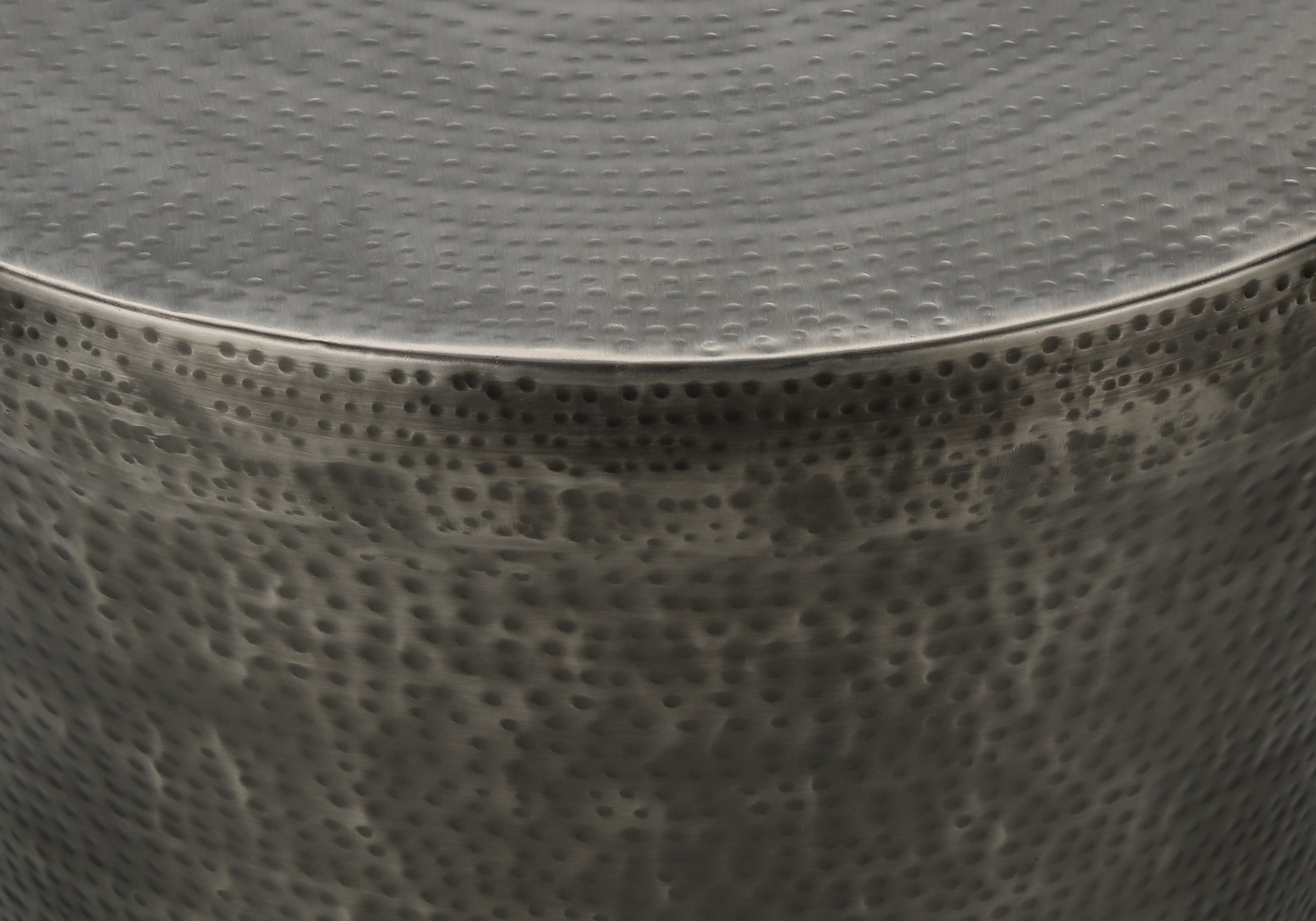 Closeup of a hammered metal side table with a silver finish