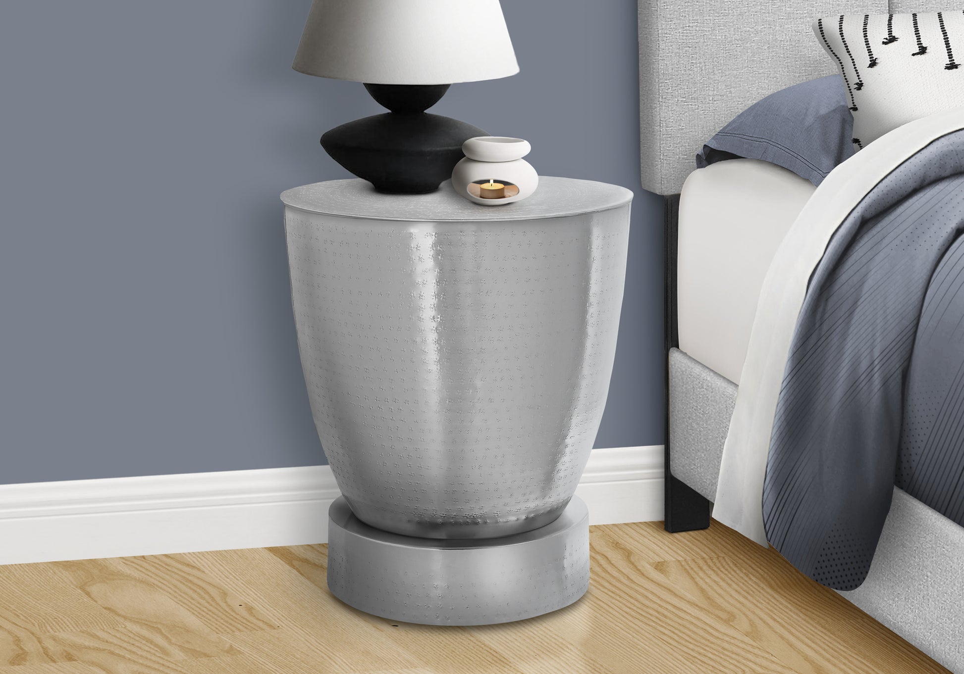 Textured silver bedside table with modern design holding a lamp and oil diffuser