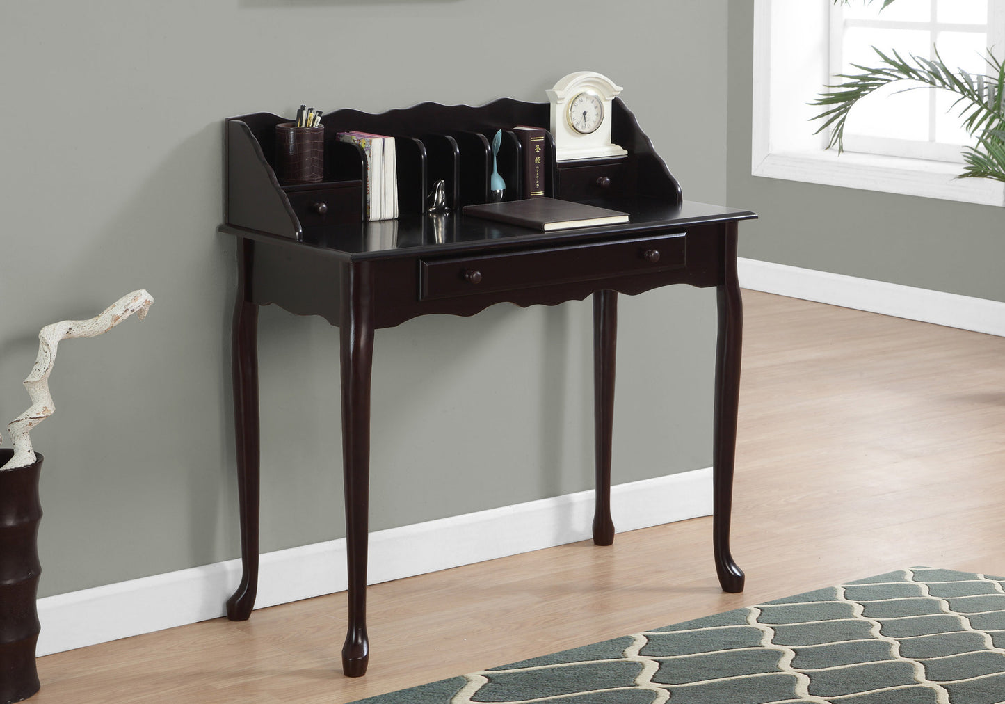 Dark wood secretary desk with scalloped top and ornate legs holding books and a clock