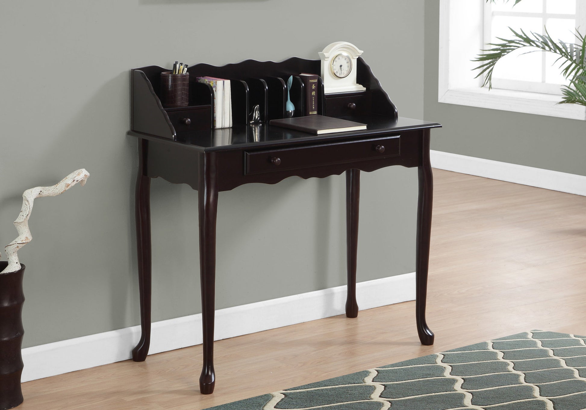 Dark wood secretary desk with scalloped top and ornate legs holding books and a clock