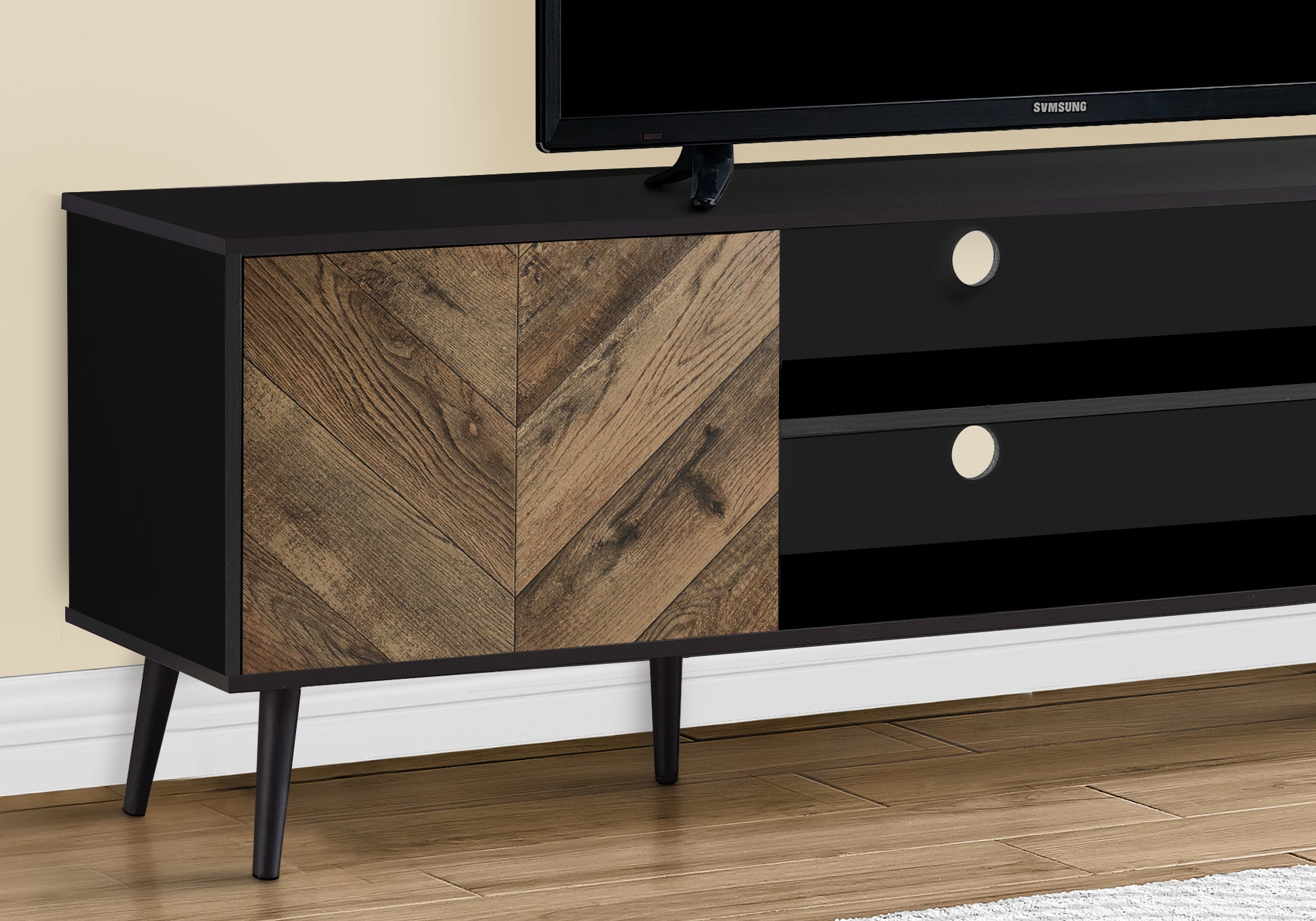 Black media console with distressed wood chevron door and tapered legs