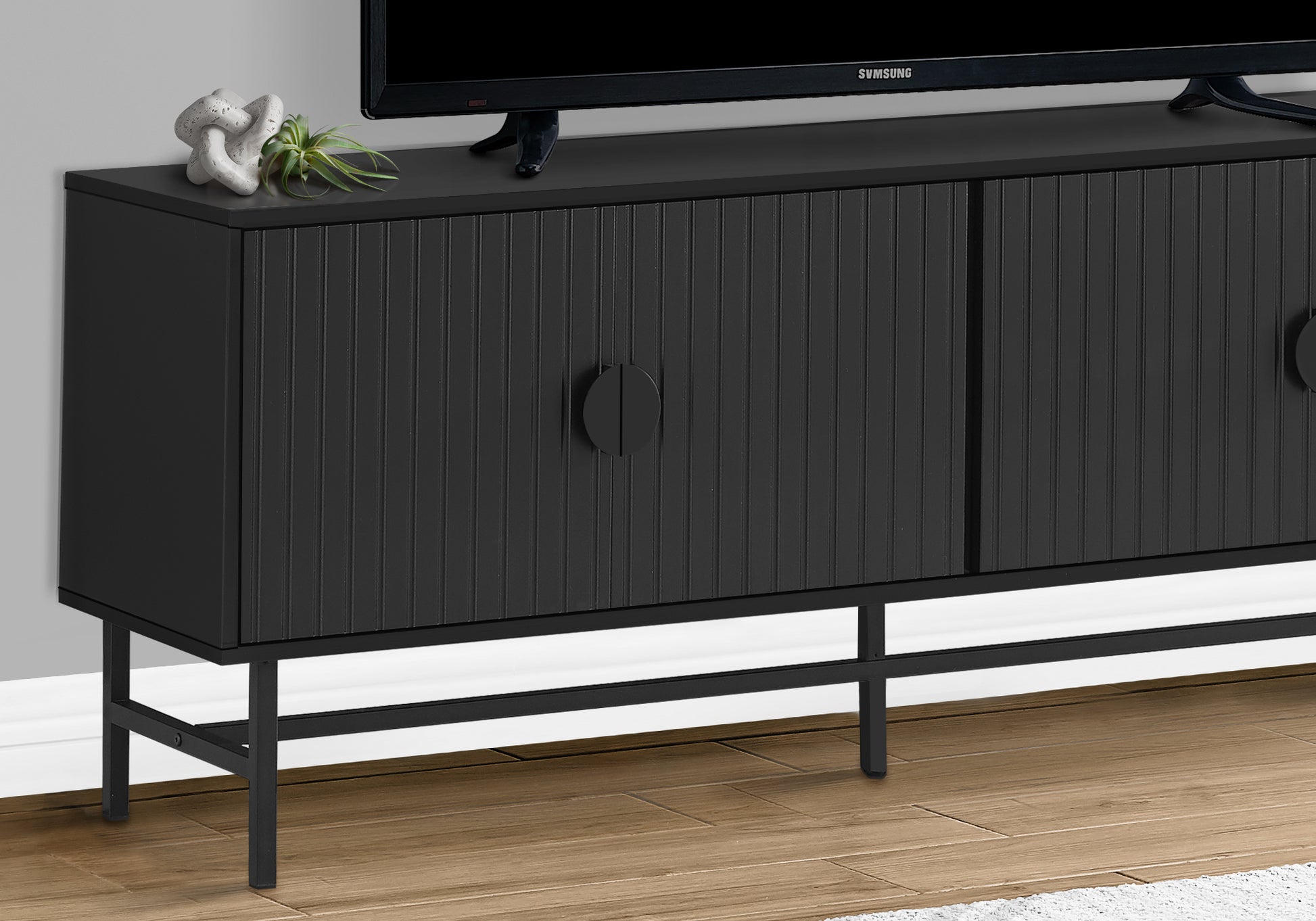Black fluted cabinet with round knobs on a thin metal base modern TV stand