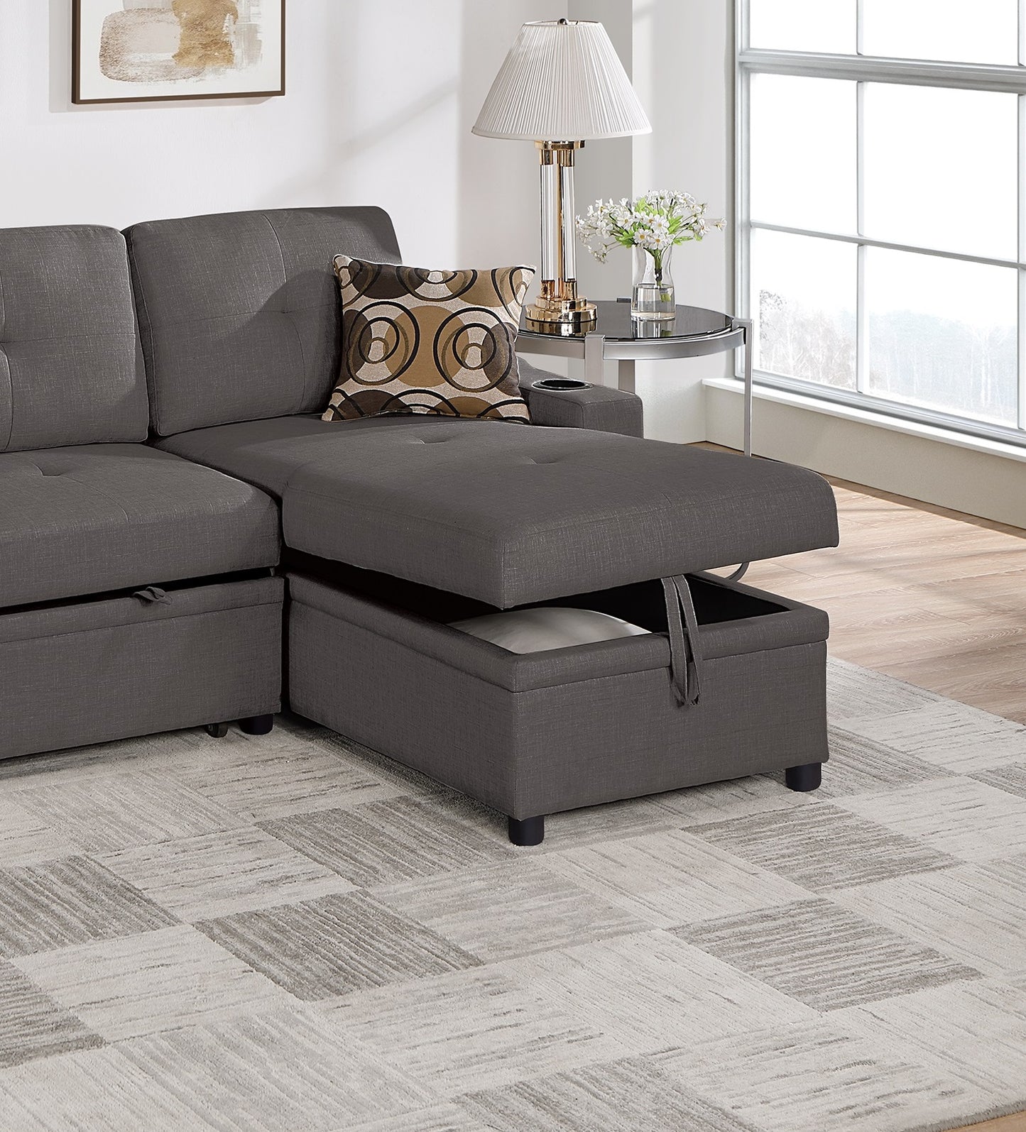 Dark grey sectional sofa with chaise lounge open revealing storage space for bedding