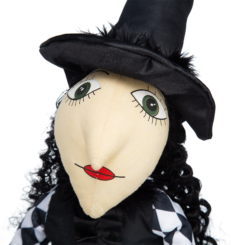 Closeup of a stuffed witch doll with a black hat and checkered outfit
