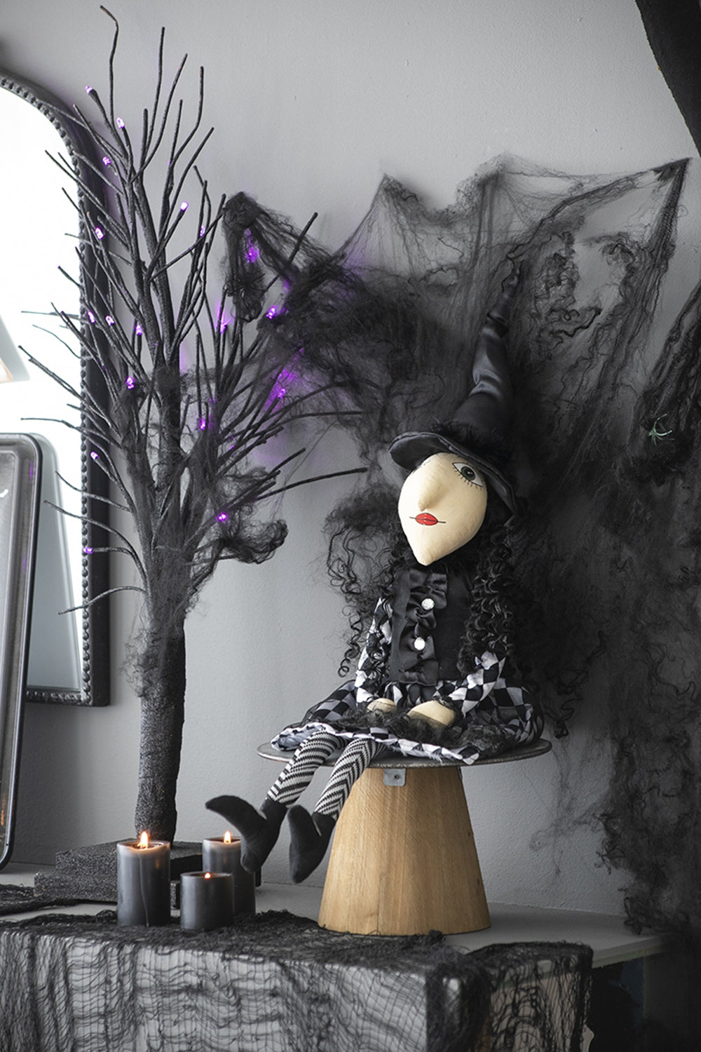 Plush witch doll in a black checkered dress with curly hair a perfect Halloween decoration