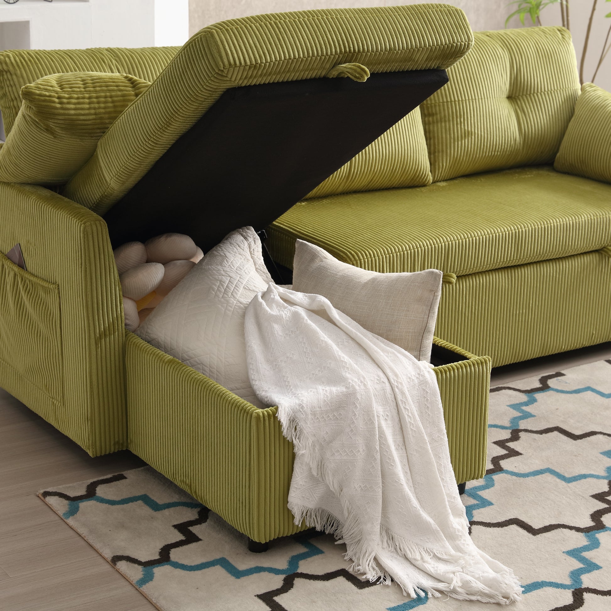 Green corduroy sofa with open storage compartment showing pillows and throw blanket