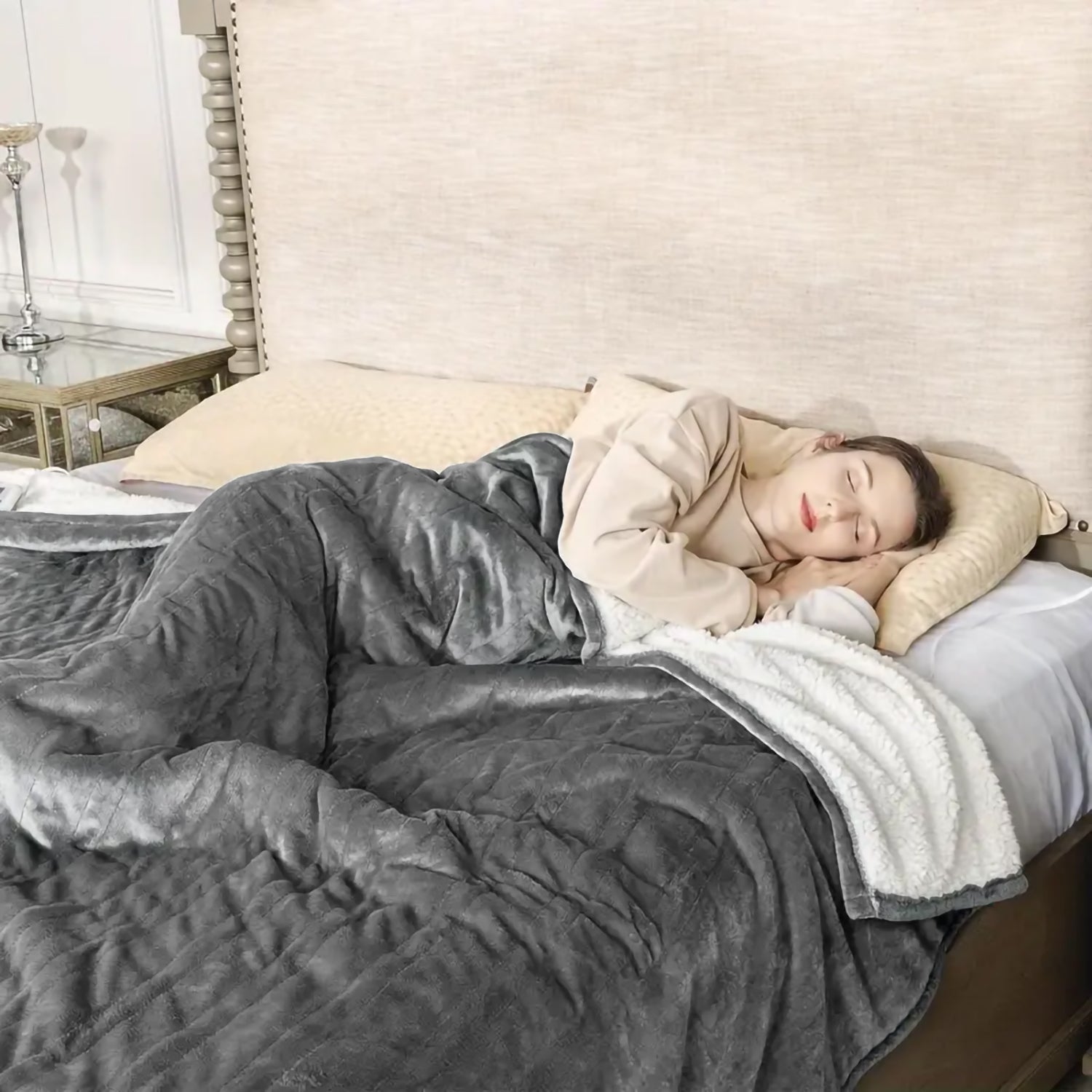 Cozy grey sherpa throw blanket with quilted pattern draped over a sleeping woman
