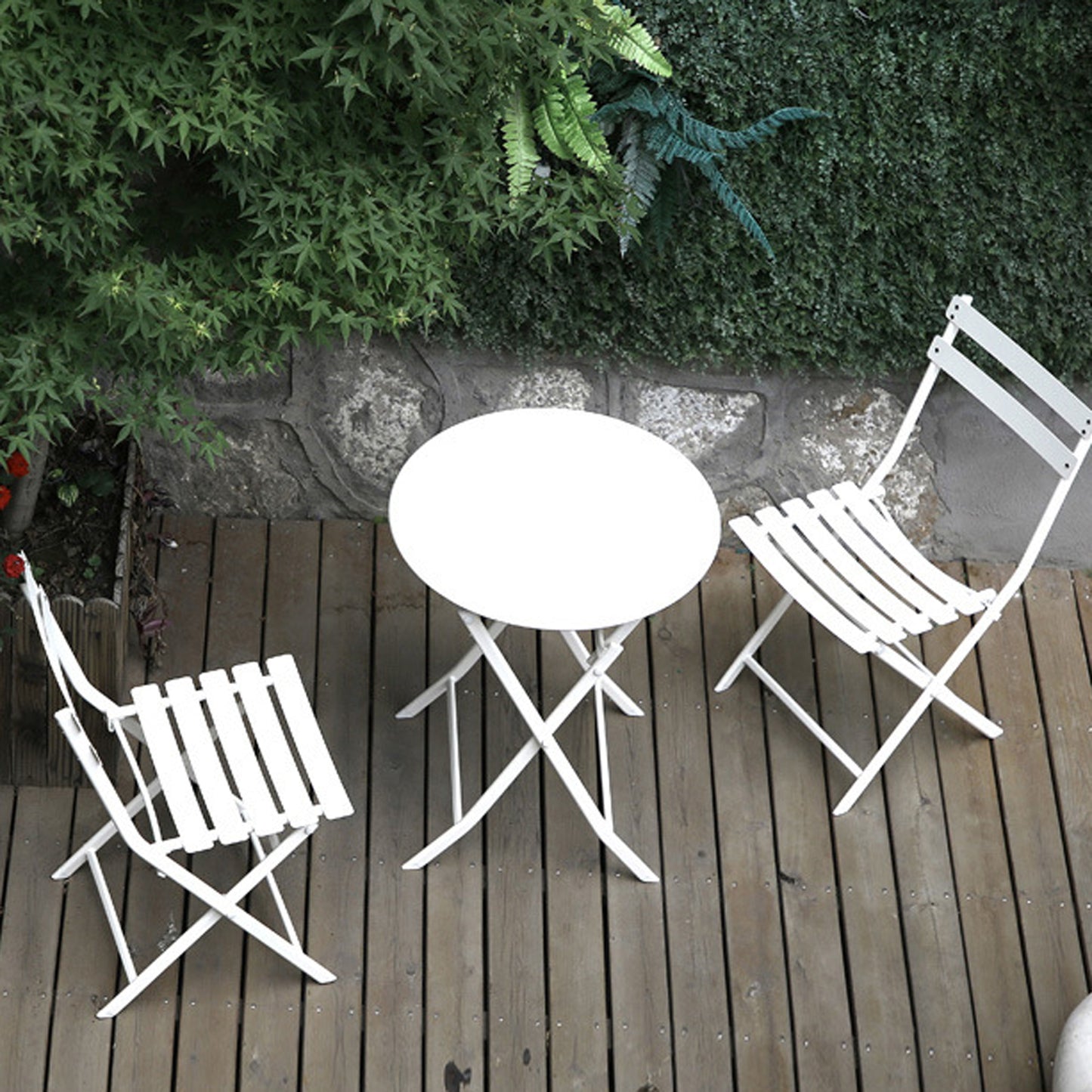 White metal bistro set with round table and two chairs on wooden deck