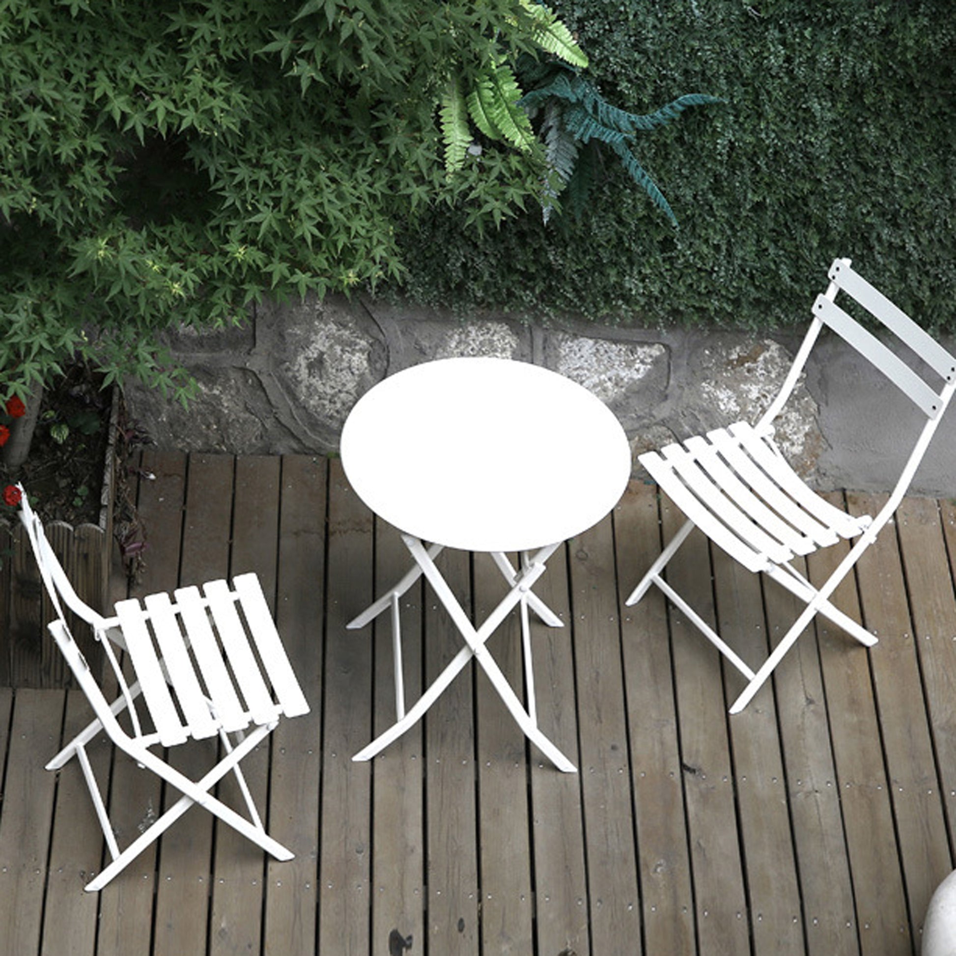 White metal bistro set with round table and two chairs on wooden deck
